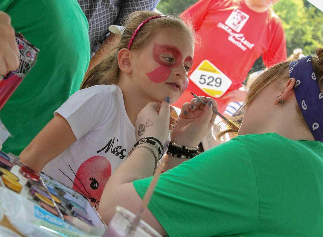 Familien.Spiele.Fest | Ein Mädchen wird geschminkt und lächelt erwartungsvoll. Inklusion in allen Bereichen.