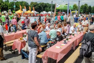 Familien.Spiele.Fest in Köln | Überblick über den Festplatz, Menschen sitzen zusammen, sind im Gespräch, essen, trinken oder machen sich gerade auf den Weg.